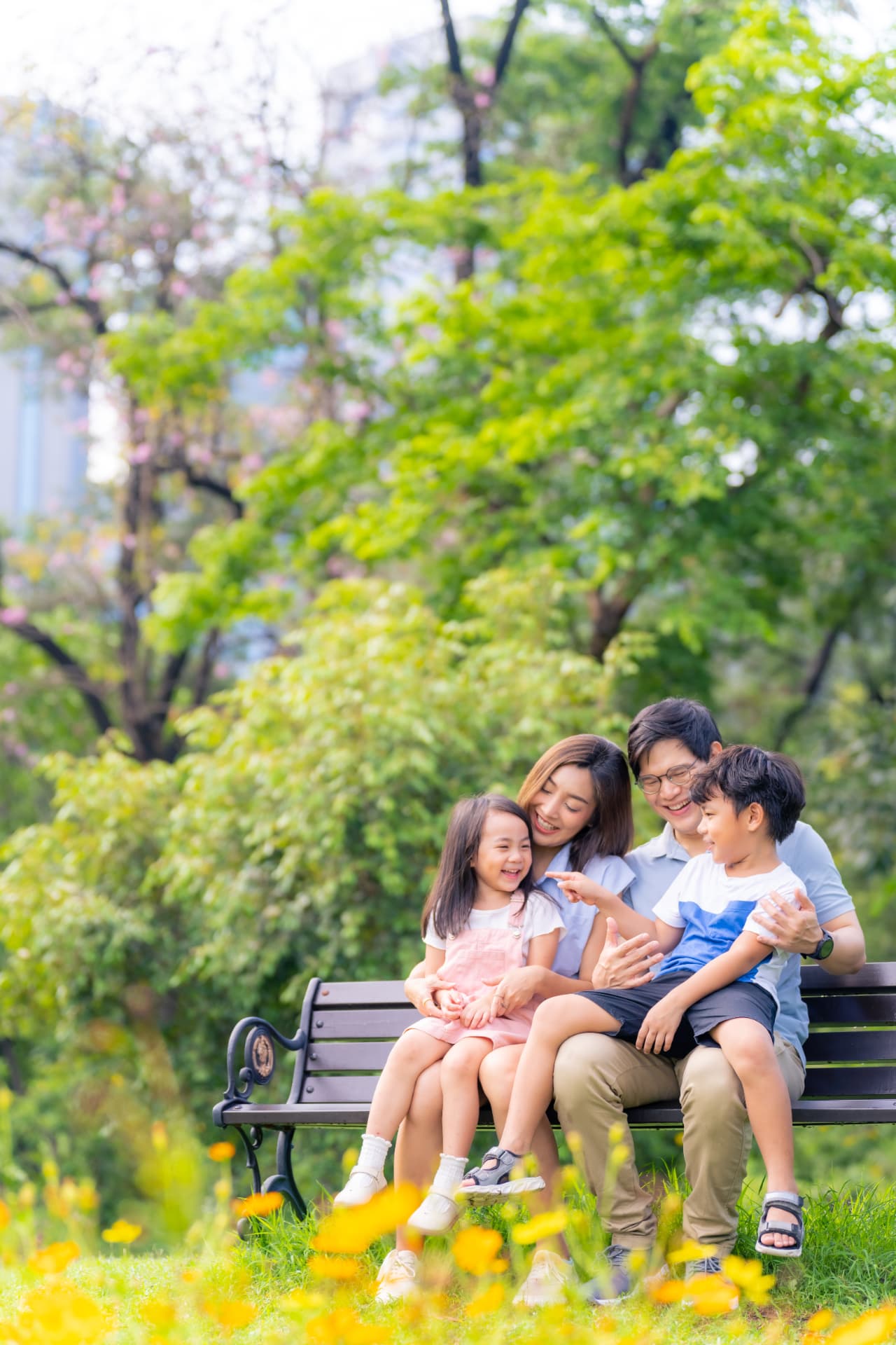 Family of four laughing together on a park bench
